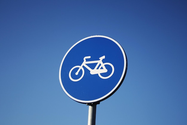 Laaghoekbeeld van een fietswegbord tegen een heldere blauwe lucht