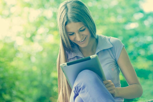 Laaghoekbeeld van een jonge vrouw die een digitale tablet gebruikt terwijl ze in het park zit