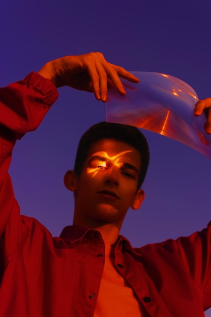 Laaghoekportret van een man die plastic vasthoudt tegen de hemel's nachts