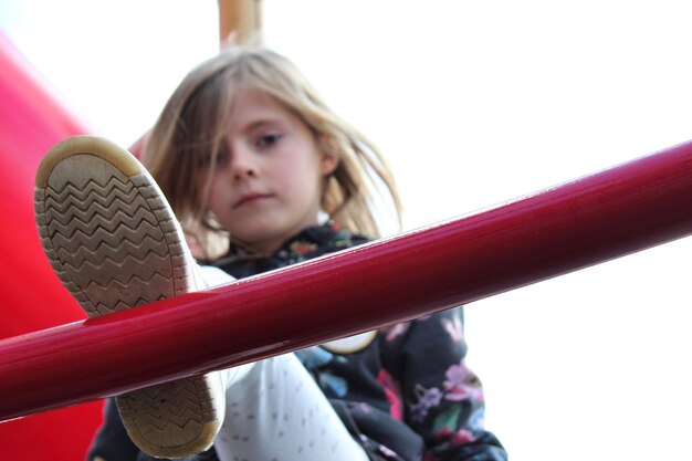 Foto laaghoekportret van een meisje dat op een ladder klimt tegen een heldere lucht op de speeltuin