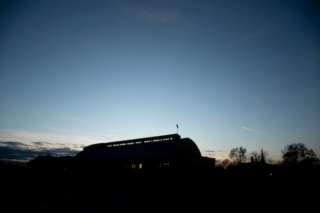 Laat in de middag silhouet van industrieel magazijn en vliegtuig door de lucht