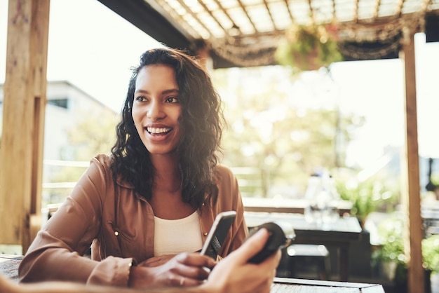 Laat uw contant geld thuis, betaal met uw telefoon shot van een jonge vrouw die draadloos betaalt in een coffeeshop