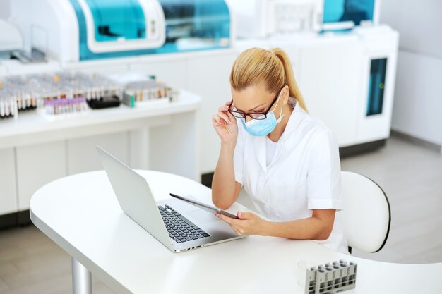 Lab assistant sitting in modern laboratory and using tablet.