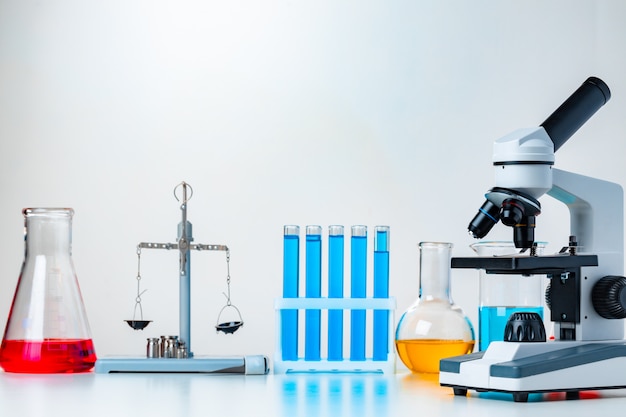 Lab microscope with laboratory glassware on desk