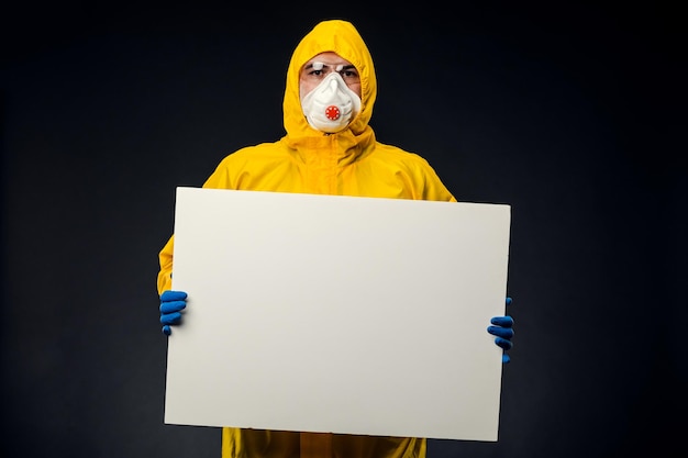 A lab scientist in a protective suit holds a blank white board on a black background.