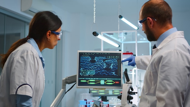 lab technicians making pharmaceutical research for antibiotics, curing disease with dna enhancing drugs working at night. team examining virus evolution using high tech for treatment against covid19