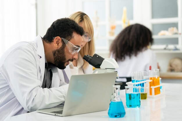 Lab worker using magnifying glass on microscope