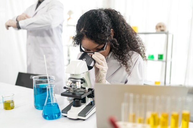 Lab worker using magnifying glass on microscope