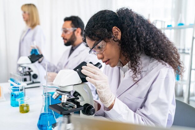 Lab worker using magnifying glass on microscope