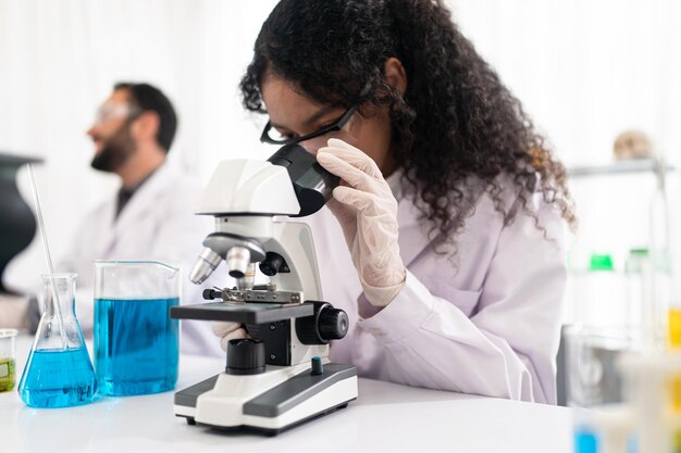 Lab worker using magnifying glass on microscope