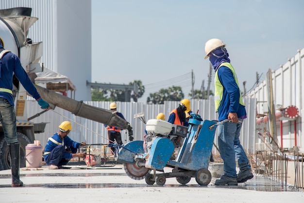 Labor or construction worker using machine cutter joint concrete for slab road pavement