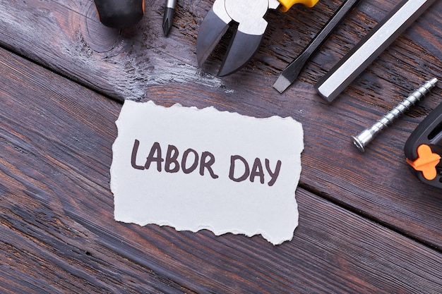 labor day card on wood. greeting paper, pliers, screwdriver. gift ideas on labor day.