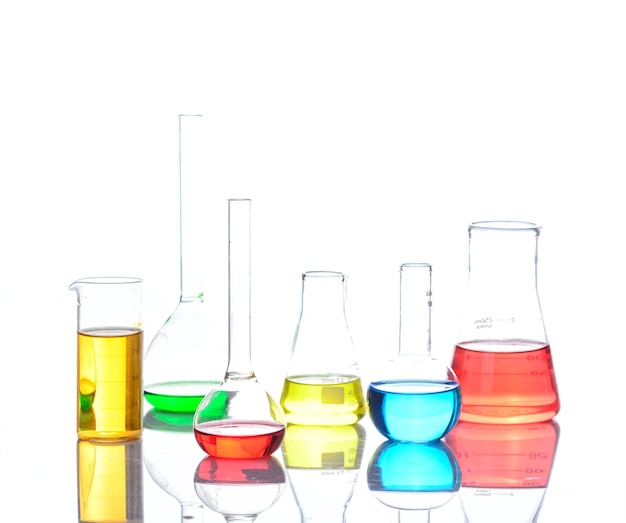 Laboratoriumglaswerk met gekleurde vloeistoffen over reflecterende tafel over wit