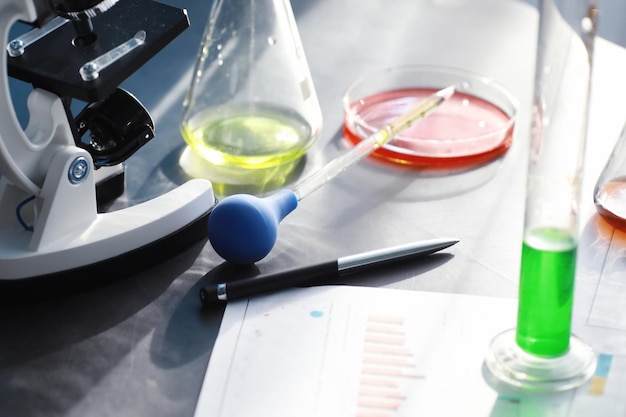 Foto laboratoriumonderzoek drugstesten chemische experimenten in het laboratorium microscoop verschillende reageerbuisjes en bekers op tafel bij de arts