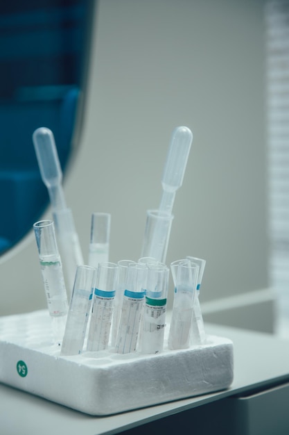 Laboratoriumreageerbuizen met papieren etiketten erop die in gaten van een plastic schuimdoos staan