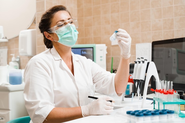 Photo laboratory assistant holds test tubes for gynecological and cytological analysis woman scientist working in medical lab