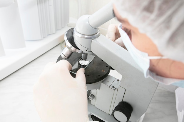 A laboratory assistant looks into a medical microscope Research analysis