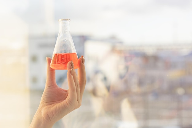 A laboratory assistant standing at the window conducts an inspection of the reagent in the flask