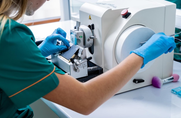 L'assistente di laboratorio lavora su una sezione del microtomo rotante e realizza vetrini per microscopio