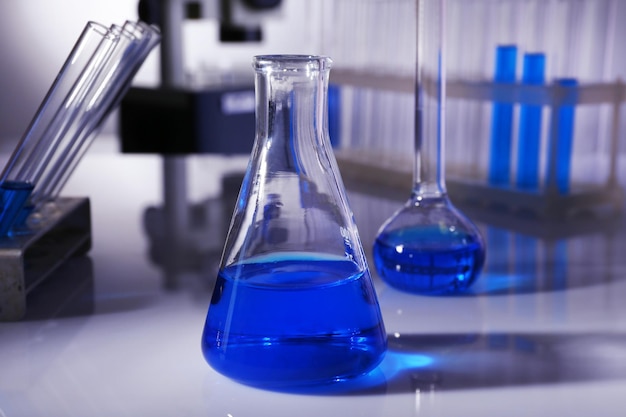 Laboratory glassware with blue liquid on gray background