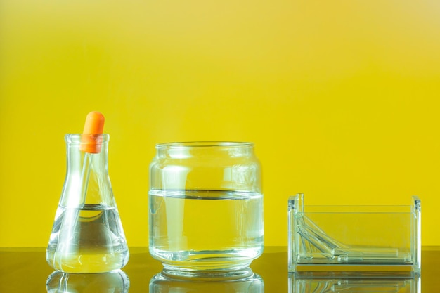 Laboratory glassware with yellow liquid on yellow\
background