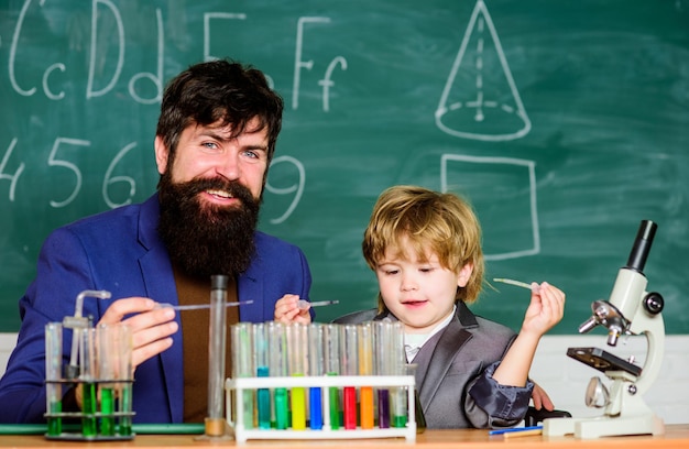 Laboratory test tubes and flasks with colored liquids father and son child at school Chemistry beaker experiment laboratory research and development bearded man teacher with little boy Be Happy
