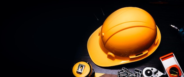 労働者の日または労働安全コンセプト コピー スペースを持つ暗い背景に安全ヘルメットとツール