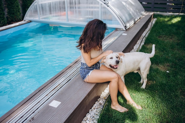 Labrador en meisje genieten in de zomer van het blauwe water van een zwembad