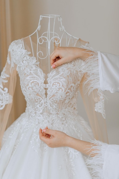 Photo lace and embroidery on fabric with beads wedding dresses on the mannequin skillful female dressmaking adjusting buttons on clothing amazing wedding dress on a mannequin