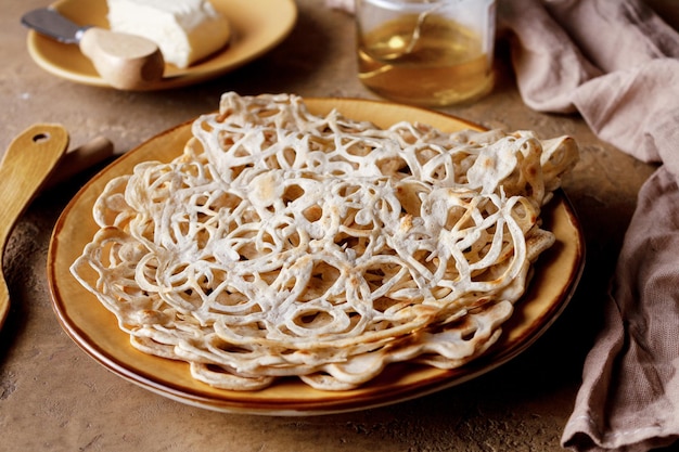 Lace pancakes on a yellow clay plate on the table