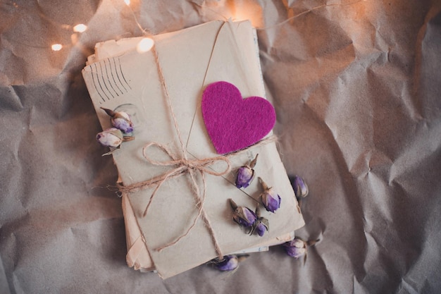 Lettere d'amore di carta cucita con petali di rose alzate sopra le luci. vista dall'alto. san valentino.