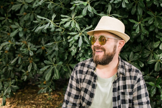 Lachen aantrekkelijke man met hoed over groene boom achtergrond met kopie ruimte en lege ruimte emotie en vakantie reizen vakantie concept