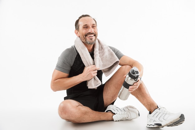 Lachen sterke volwassen sportman zitten met handdoek en water