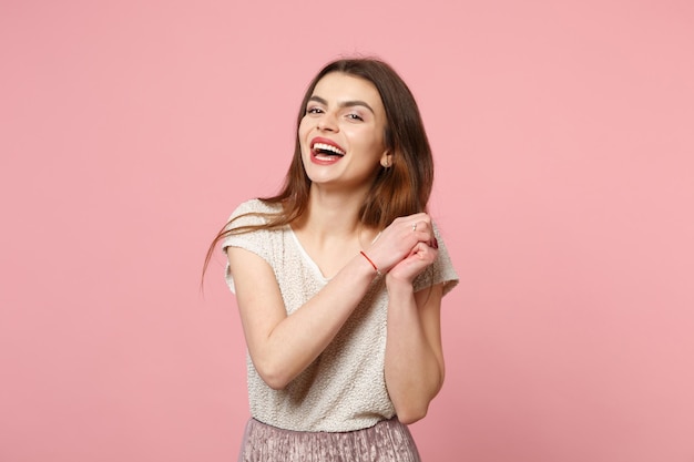 Lachen vrolijke jonge vrouw in casual lichte kleding poseren geïsoleerd op pastel roze muur achtergrond, studio portret. Mensen oprechte emoties levensstijl concept. Bespotten kopie ruimte. Handen vasthouden.