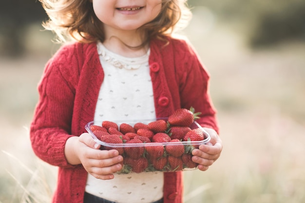 Lachend babymeisje dat verse rode aardbei houdt