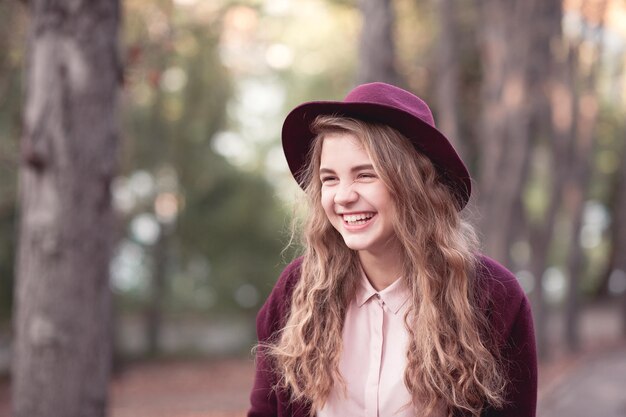 Lachend tienermeisje met stijlvolle hoed en winterjas
