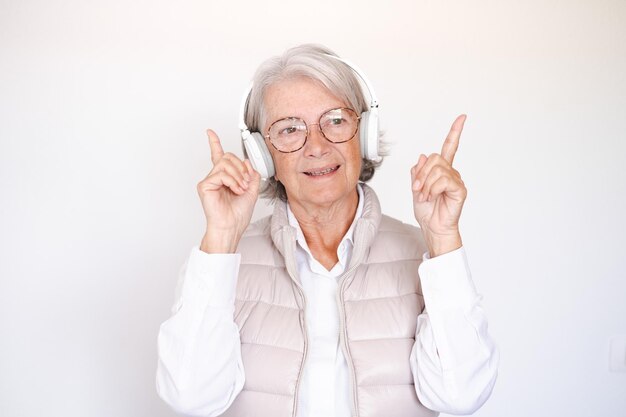 Lachende aantrekkelijke senior vrouw zingen genieten van muziek luisteren liedjes met koptelefoon