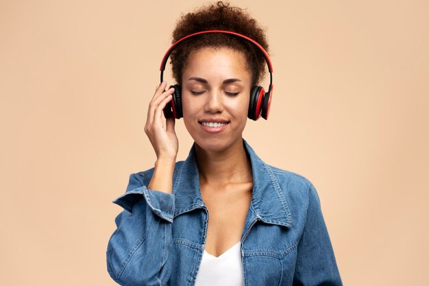 Lachende Afro-Amerikaanse vrouw die muziek luistert met gesloten ogen in draadloze hoofdtelefoons