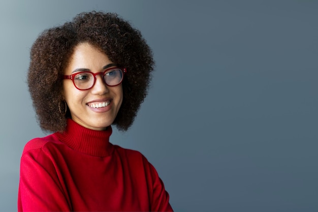 Lachende Afro-Amerikaanse zakenvrouw met stijlvolle bril en rode coltrui