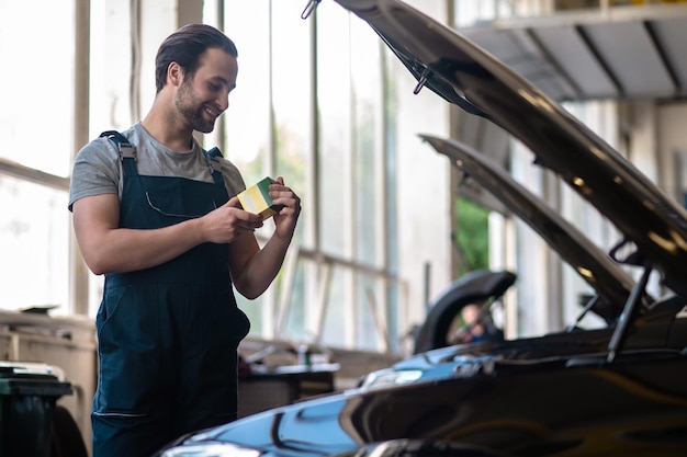 Lachende automonteur op zijn werkplek