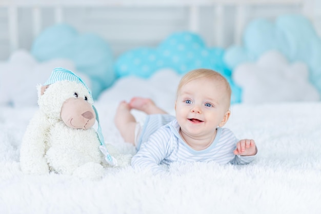 Foto lachende baby op het bed met een speelgoed wakker werd in de ochtend of gaat naar bed gelukkige baby