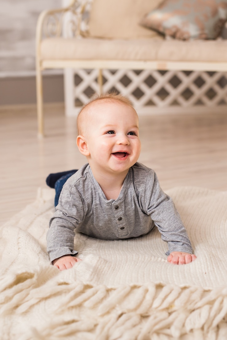 Foto lachende babyjongen liggend op buik thuis.