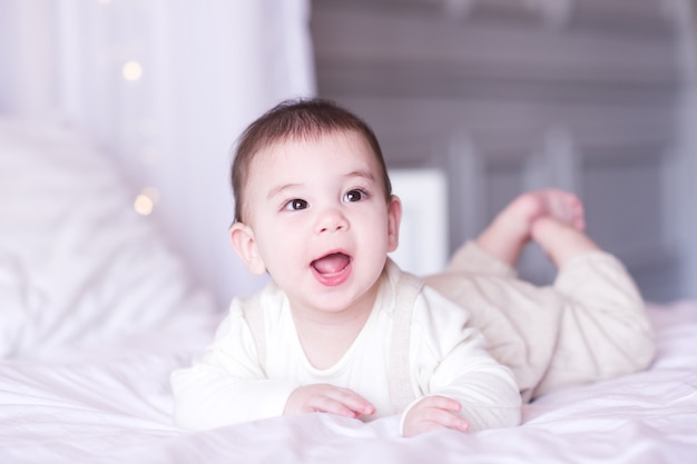 Lachende babyjongen onder de 1 jaar oud liggend in bed close-up. Goedemorgen. Jeugd.