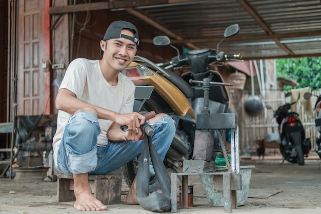 Lachende bandenplakster zit over een lekkende binnenband te wrijven in een motorreparatiewerkplaats