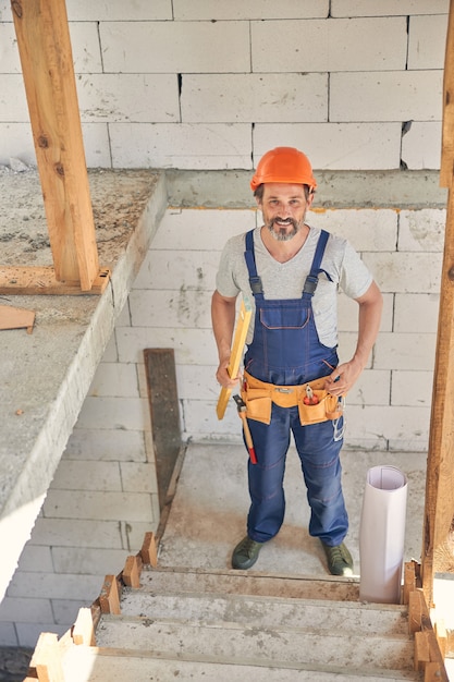 lachende bebaarde volwassen in een helm die op de trap staat