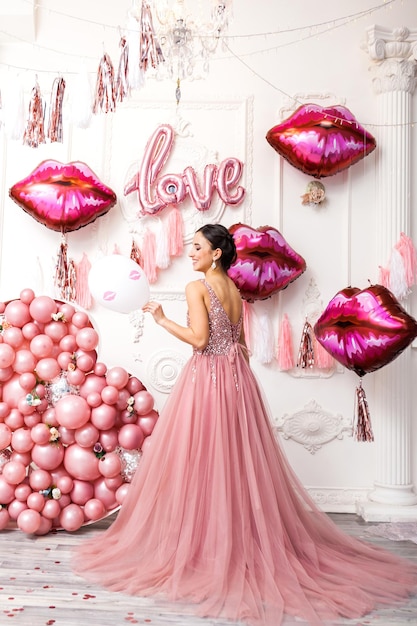 Lachende blij verraste vrouw in tule jurk met roze ballons lippen