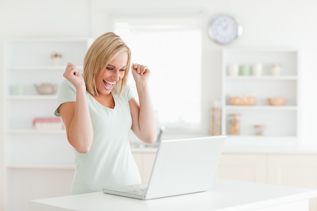 Lachende blonde vrouw die laptop bekijkt