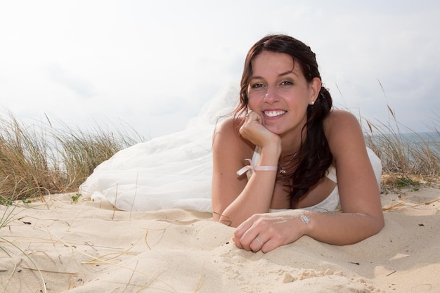 Lachende bruid liggend op het zand in de zee