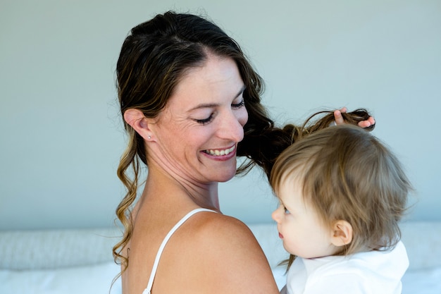 lachende brunette vrouw met een schattige baby die met haar haar speelt