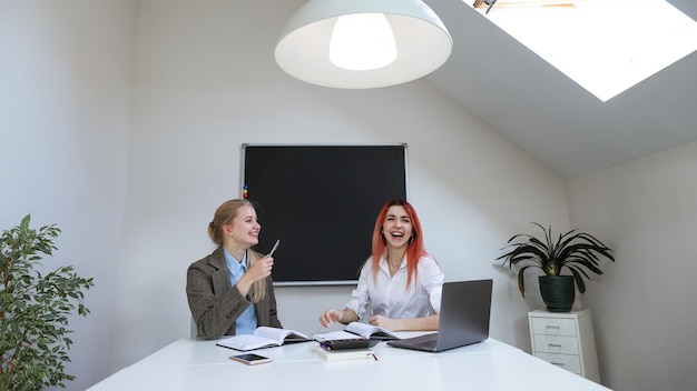 Lachende collega's tijdens een werkdag op kantoor Stijlvol kantoor Laptop op tafel